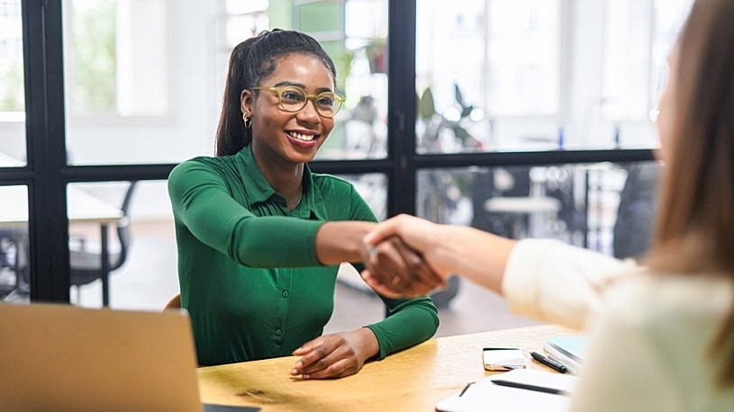 Businesswoman shaking hands across desk with client