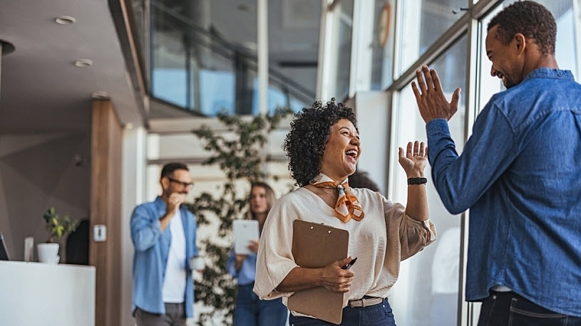 Smiling colleagues exchange high fives in modern office How Retirement Benefits Create Business-Wide Advantages
