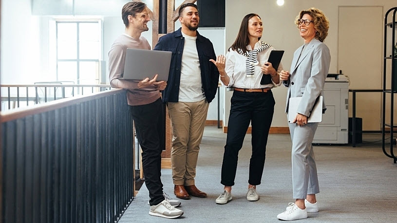 Smiling manager meets with diverse team in office hallway Actionable Strategies for Leadership and Success with Mel Robbins