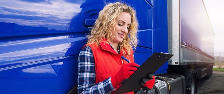 woman by long haul truck looking at paperwork woman by long haul truck looking at paperwork