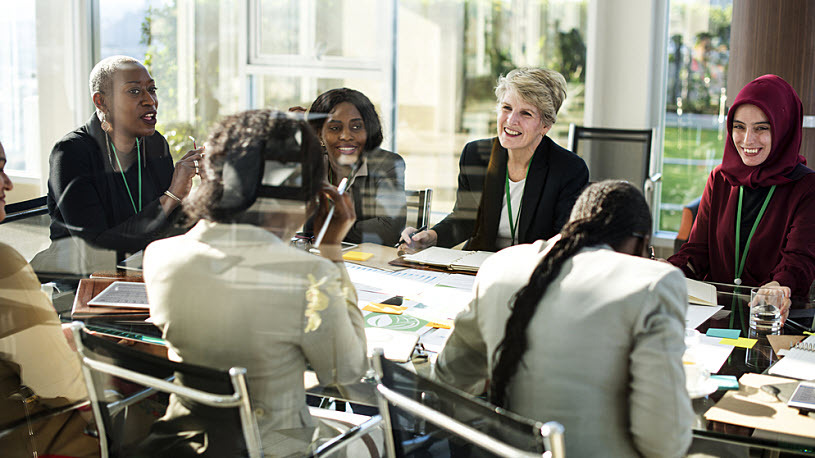Women in leadership A group of diverse women seated and talking at a conference table.