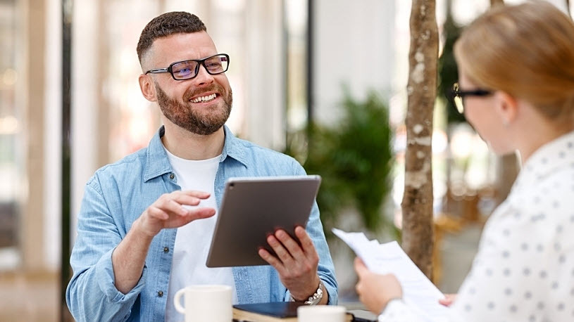 male and female coworkers chat over coffee using tablet computer male and female coworkers chat over coffee using a tablet computer