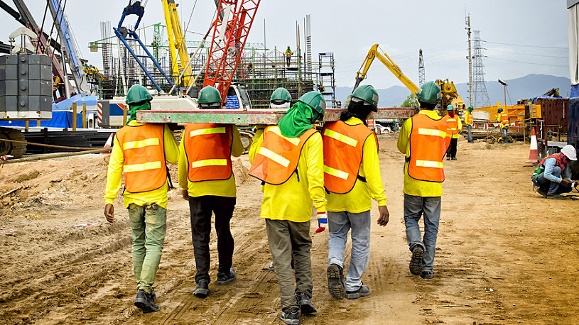 group of construction workers carrying heavy panel at worksite
