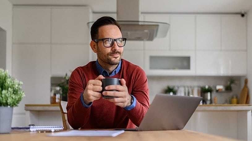 White male holds coffee mug at kitchen table pensive
