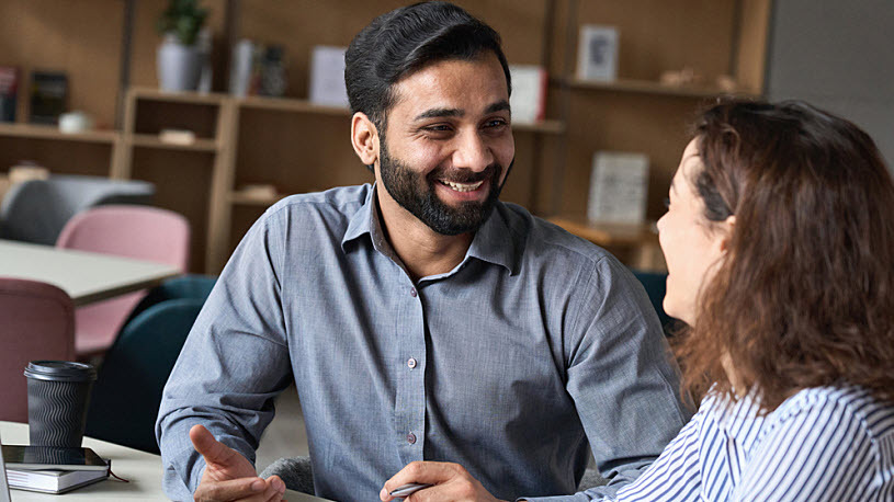 Payroll Specialist A young Indian payroll specialist discusses HR software with coworker