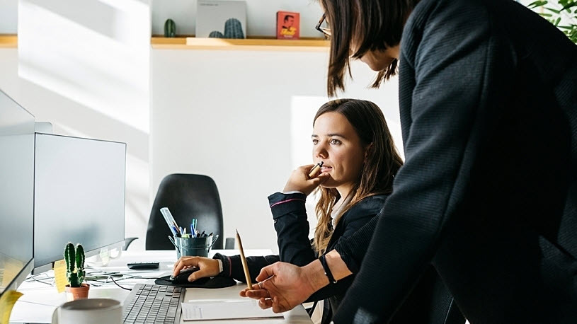 A serious businesswoman sits at desk computer listens to collegue 5 Ways to Establish Strong Business Security