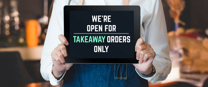 Restaurant worker holding sign promoting takeout orders only Restaurant worker holding sign promoting takeout orders only
