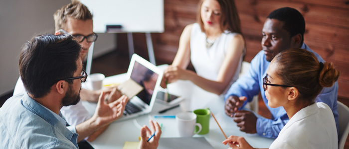 A group of employees sit at a table and discuss company culture. A group of employees sit at a table and discuss company culture.