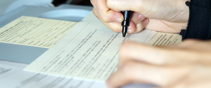 Is Rescinding the Entrepreneur Visa Good for Business? An employee signs a written form.