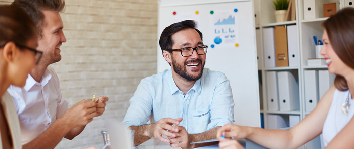 managing the company experience Employees laugh during a meeting.